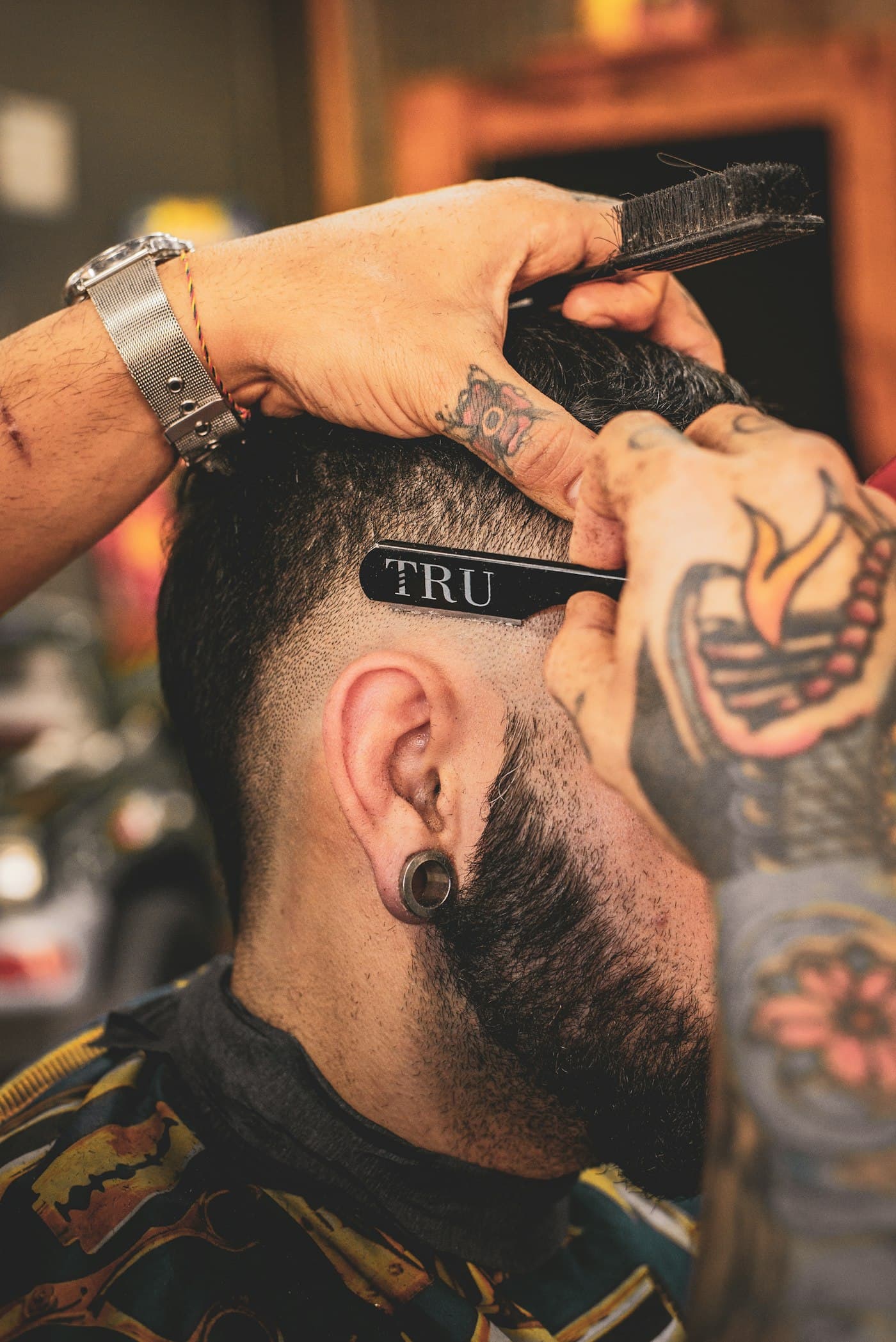 Barber hrebeňom vyťahuje líniu krátkeho strihu a brady.